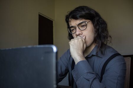 man with long hair and glasses working from home on financial issuesの写真素材