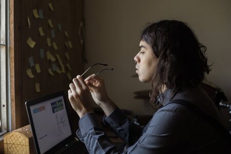 man with long hair and glasses working from home on financial issuesの写真素材