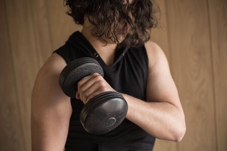 A guy exercising at home with dumbbells, stretching, shoulder exercises and boxing warm-upの写真素材