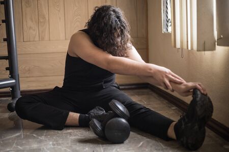 A guy exercising at home with dumbbells, stretching, shoulder exercises and boxing warm-up