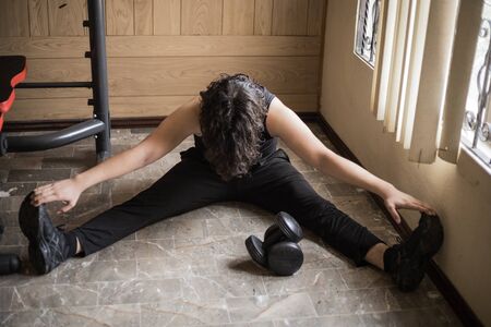 A guy exercising at home with dumbbells, stretching, shoulder exercises and boxing warm-upの写真素材