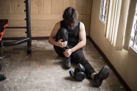 A guy exercising at home with dumbbells, stretching, shoulder exercises and boxing warm-upの写真素材