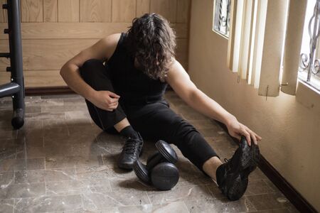 A guy exercising at home with dumbbells, stretching, shoulder exercises and boxing warm-upの写真素材