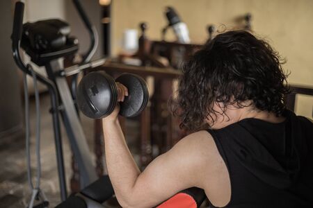 A guy exercising at home with dumbbells, stretching, shoulder exercises and boxing warm-upの写真素材