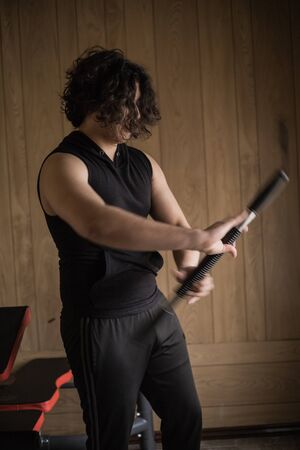 A guy exercising at home with dumbbells, stretching, shoulder exercises and boxing warm-upの写真素材