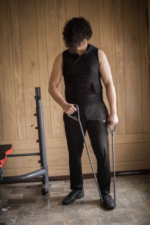 A guy exercising at home with dumbbells, stretching, shoulder exercises and boxing warm-upの写真素材