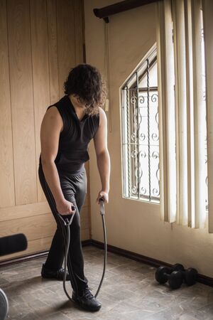 A guy exercising at home with dumbbells, stretching, shoulder exercises and boxing warm-upの写真素材