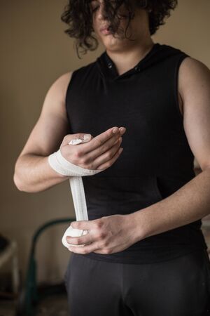A guy exercising at home with dumbbells, stretching, shoulder exercises and boxing warm-upの写真素材
