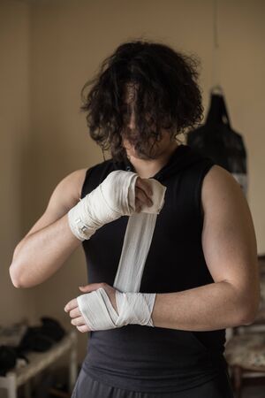 A guy exercising at home with dumbbells, stretching, shoulder exercises and boxing warm-upの写真素材