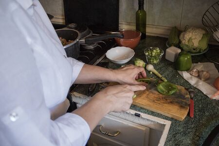 housewife cooking lasagna with vegetables in a white wooden kitchenの写真素材