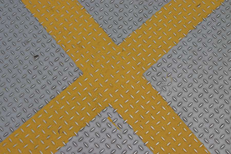 Yellow cross on textured steel sheetの写真素材