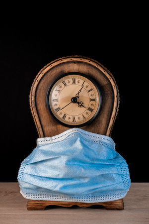 Clock with mask on black backgroundの写真素材