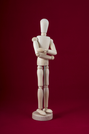 a wooden dummy posing with his arms folded with a red backgroundの写真素材
