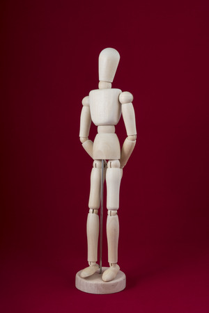 A wooden dummy posing on a red backgroundの写真素材