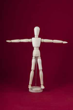 A wooden dummy posing for a dance with a red backgroundの写真素材
