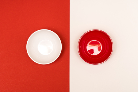 red and white bowls arranged opposite each other on a colored backgroundの写真素材