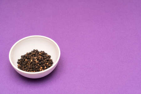 black pepper in a bowl on a colored backgroundの写真素材