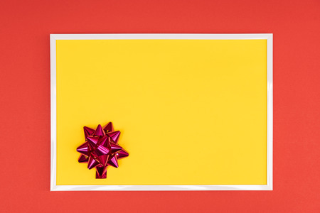 Christmas decorative bow in a white frame on a colored backgroundの写真素材