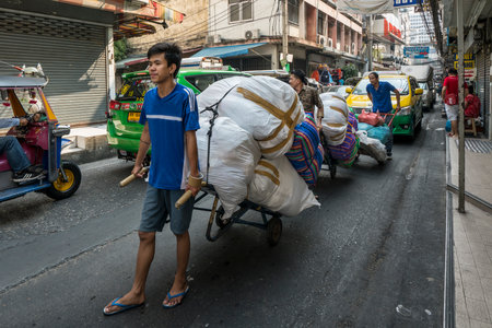 Men carrying goods with a cart on the bangkok roadのeditorial素材
