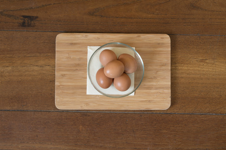 some eggs in a glass bowl on a wooden tableの写真素材