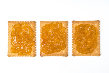 Some dry biscuits with jam on a white surfaceの写真素材