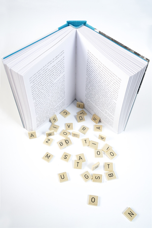 Letters falling from a book on a white tableの写真素材