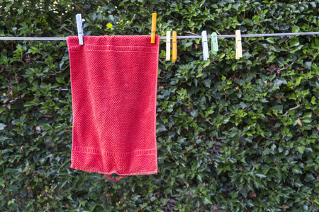 a red towel hanging to dry outdoors in the garden