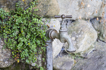 an old faucet on a stone wallの写真素材