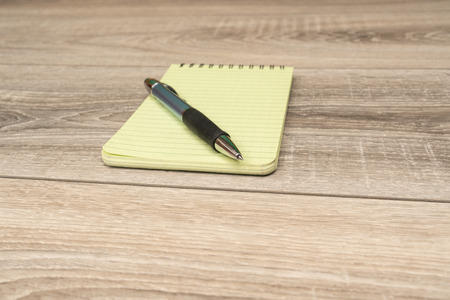 an empty block and a pen on the wooden table