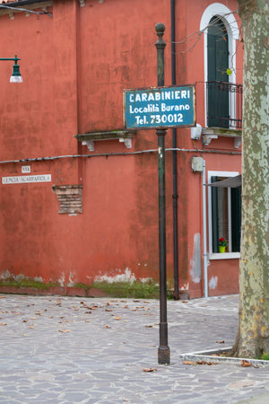 an old sign indicating the telephone number of the carabinieri in the streets of Burano island, Venice, Italyのeditorial素材