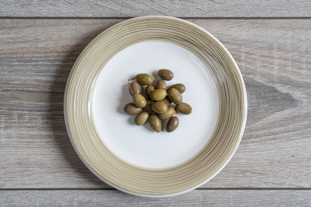 some olives in the plate on a wooden tableの写真素材