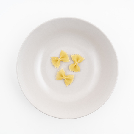 Three pieces of dried butterfly format pasta on the plateの写真素材