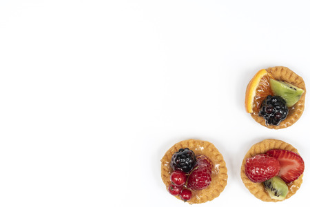 some round pastries with mixed fruit on a white surfaceの写真素材