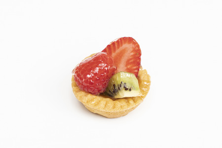 A round pastry with mixed fruit on a white surfaceの写真素材