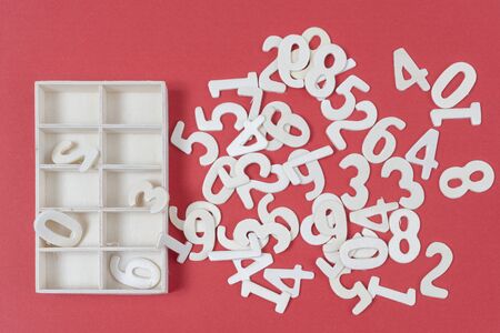 some numbers of white wood with a small box to hold them on a colored surface