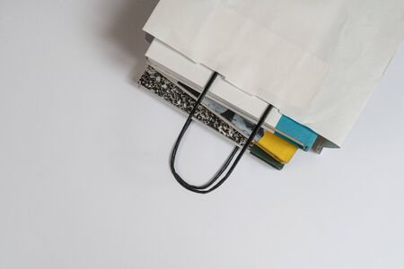 some books inside a white paper bag on the table