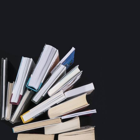 a series of books arranged like a fan on a black surface seen from aboveの写真素材