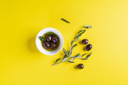 Olive oil and olives on a yellow surface with some Olive branchesの写真素材
