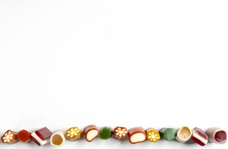 a row of colorful candies of various shapes on a white surfaceの写真素材