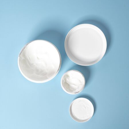  jars of moisturizer cream on a blue surfaceの写真素材