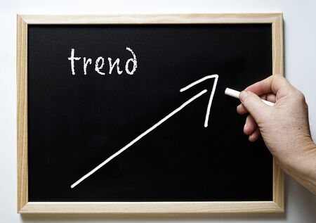 a blackboard with writing trend and an arrow indicating the riseの写真素材
