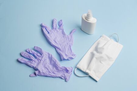 protective masks, disinfectant and disposable latex gloves on a colored surfaceの写真素材