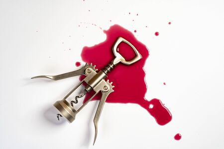 a corkscrew on a patch of wine on a white surfaceの写真素材