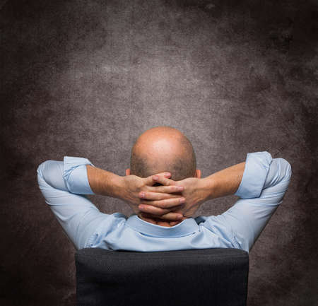 a relaxed man shot from behind with a gray backgroundの写真素材