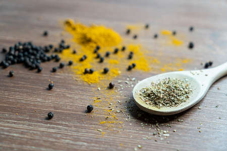 a wooden ladle with curry powder and pepper grainの写真素材