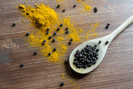 a wooden ladle with curry powder and pepper grain