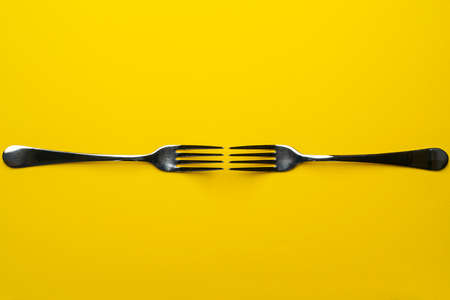 two forks with some types of colored pasta on a yellow surfaceの写真素材