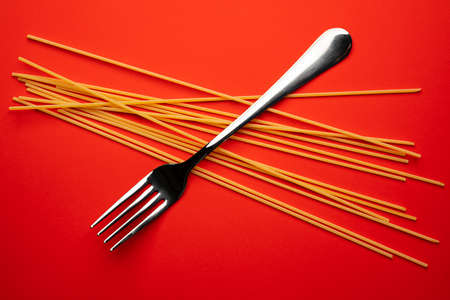 two forks with some types of colored pasta on a yellow surfaceの写真素材