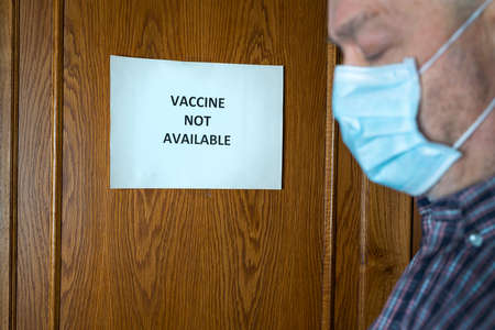 A man in front of a closed door with a sign that reads Closed because the vaccine is not availableの写真素材