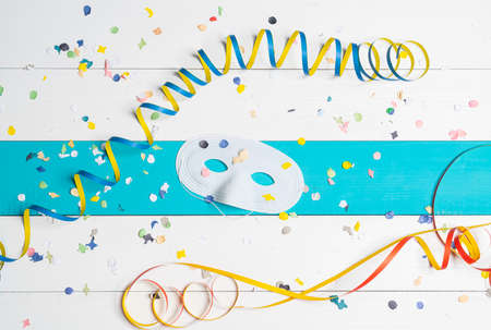 masks, confetti and streamers on a colorful carnival tableの写真素材